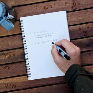 Airpress ballpoint pen in blue grey writing on a wet notebook page – Shibuya Stationery Store
