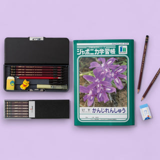 Bundle of pencils in a black case with a notebook featuring purple flowers on a light purple background - Shibuya Stationery