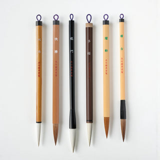 Array of six Japanese calligraphy brushes from brand Kuretake with wooden handles on a white background - Shibuya Stationery Store