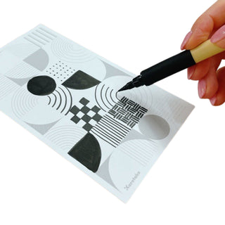 Hand holding a Kuretake Bimoji Fude Pen drawing on a paper with geometric designs - Shibuya Stationery Store