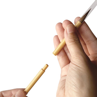 Hands holding two halves of a small brush pen from the Kuretake small calligraphy box against a white background - Shibuya Stationery Store