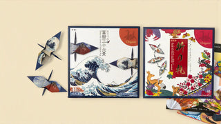 Two Japanese origami paper packs—The Great Wave and Orifuda designs—displayed with folded paper cranes on a beige background.