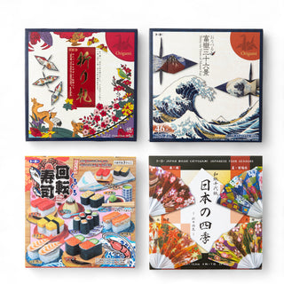 Set of four Japanese origami paper packs by Toyo featuring designs inspired by Mount Fuji, traditional patterns, sushi, and four seasons, arranged in a flat lay.