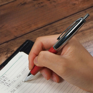 Filare Wood Ballpoint Pen Wood Silver writing in a notebook on a wood-grain desk – Shibuya Stationery