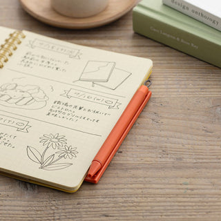 Zebra Pitan Ballpoint Pen Holder for Notebooks 0.5 Orange attached to notebook with pen inserted – Shibuya Stationery