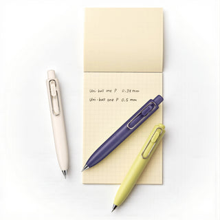 Three bundled uni-ball one P Gel 0.5mm tip pens by Mitsubishi Pencil on a white background with a small grid style notebook displaying pen specifications - Shibuya Stationery Store